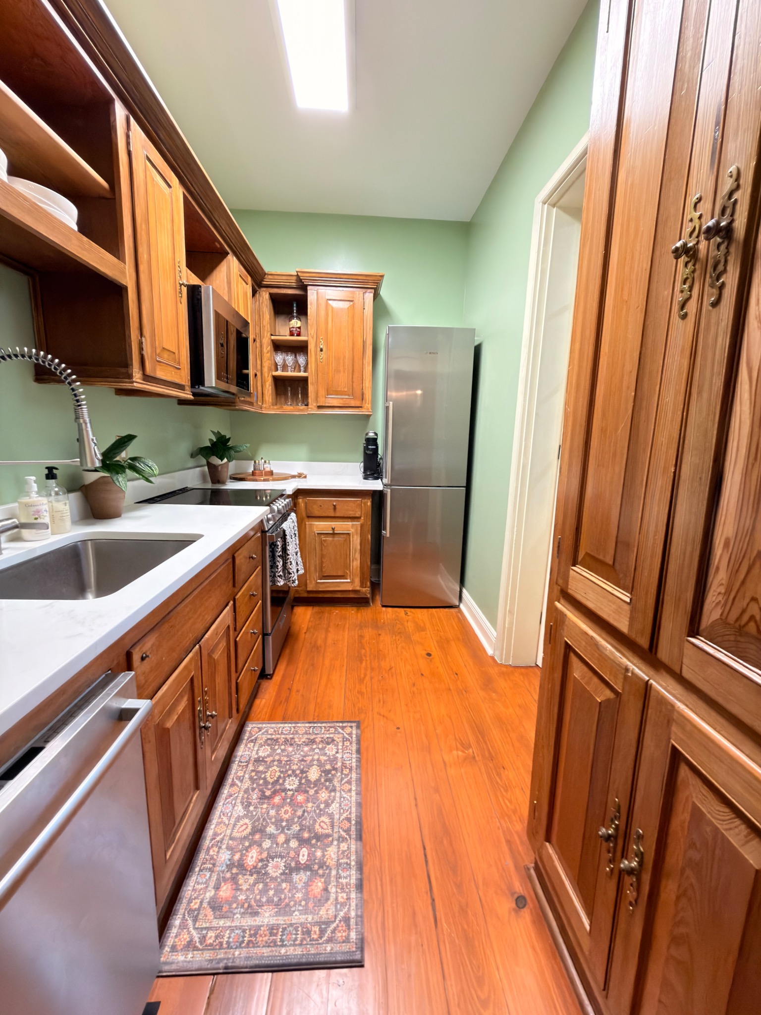 Compact kitchen with wood cabinetry and green walls