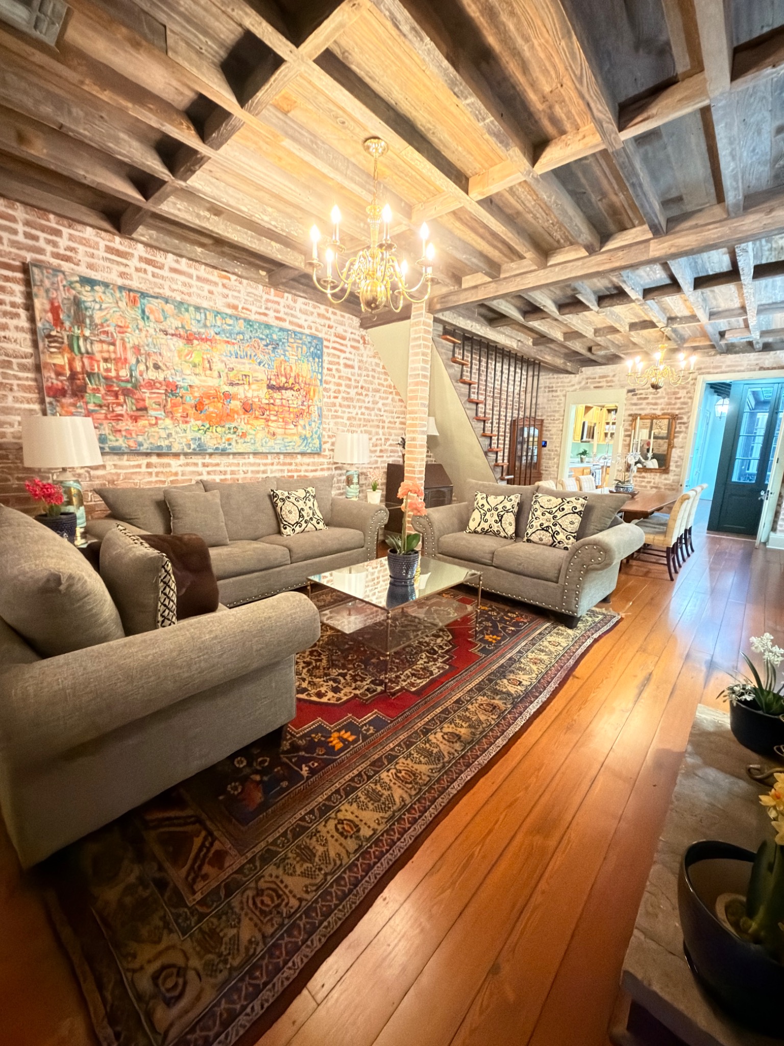 Living room with exposed brick, historic reclaimed cypress ceiling and chandeliers